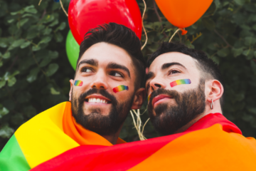 happy gay couple with lgbt balloons hugging garden bij COC Midden-Nederland